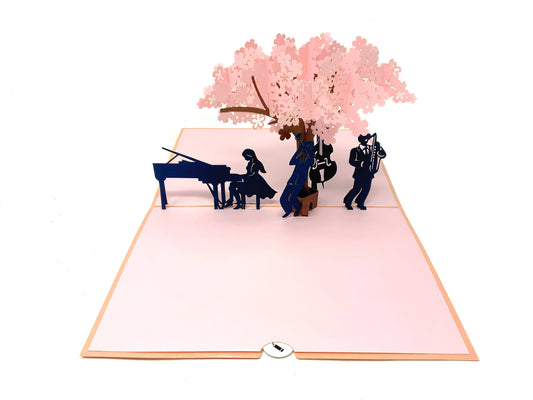 &quot;Musicians under blossom tree pop-up card: A three-dimensional card with an intricately crafted pop-up scene featuring charming musicians performing under a blossoming tree, creating a delightful and artistic setting.&quot;