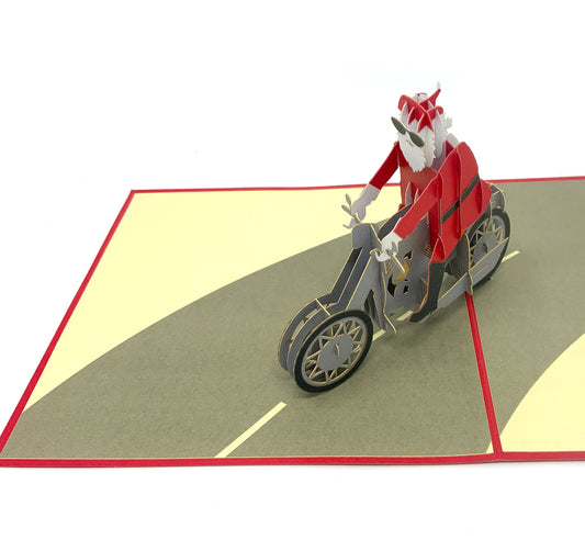 &quot;Santa on Motorbike pop-up card: A three-dimensional card with an intricately crafted pop-up scene featuring Santa Claus riding a festive motorbike, perfect for adding a touch of holiday adventure to various occasions.&quot;